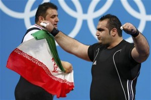 Iran's Behdad Salimikordasiabi and compatriot Sajjad Anoushiravani Hamlabad celebrate winning gold and silver respectively at the end of their men's +105kg Group A weightlifting competition during the London 2012 Olympic Games