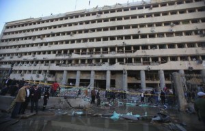Police officers and people gather in front of damaged Cairo Security Directorate after bomb attack in Cairo