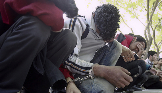 Handcuffed suspects sit on the ground after officers arrest and detain suspected drug users and dealers during a sweep in a southern neighbourhood of Tehran