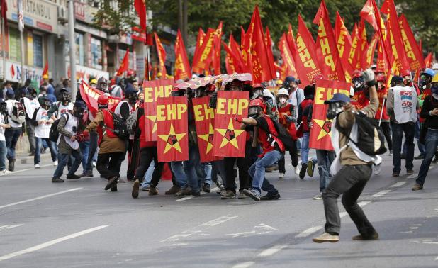 Protester takes aim at riot police with a slingshot during a May Day demonstration in Istanbul