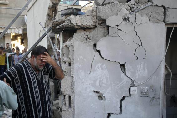 A Palestinian man reacts as he stands next to the wreckage of a house in Rafah