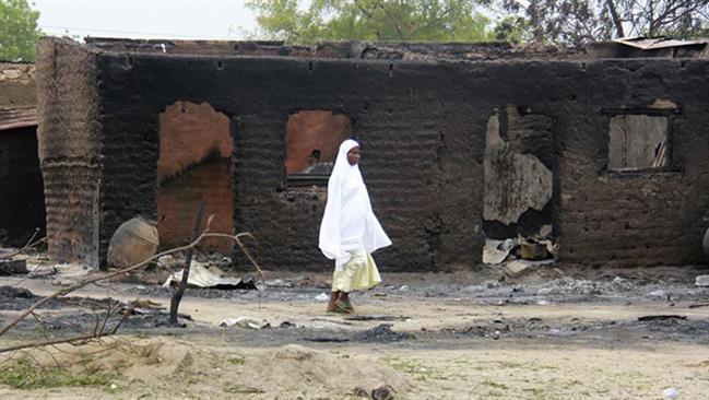 A woman walks past burned houses in the remote town of Baga