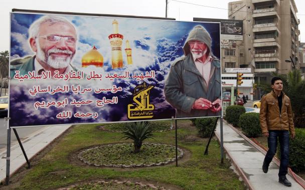 A man walks past a billboard featuring photographs of Iranian General Hamid Taghavi of the Iraqi Shi'ite militia group Saraya al-Khorasani, who was killed during fighting against the Islamic State in northern Iraq in December, in Baghdad January 26, 2015. REUTERS/Ahmed Saad