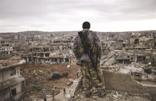 A Kurdish marksman stands atop a building as he looks at the destroyed Syrian town of Kobane. Around 3,000 ISIL militants who have retreated from Kobane have entered or ar expected to cross into Turkey, according to M?T. AFP Photo.